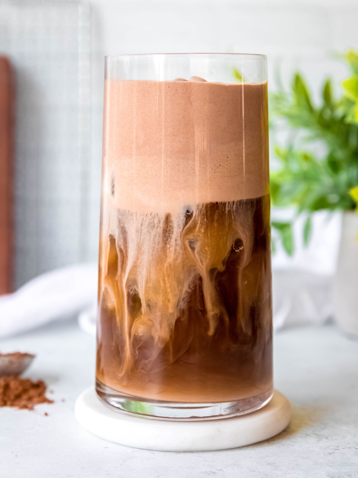 side on shot of a starbucks copycat chocolate cream cold brew in a tall, clear glass. you can see wisps of the chocolate cold foam trickling down and mixing with the cold brew layer.