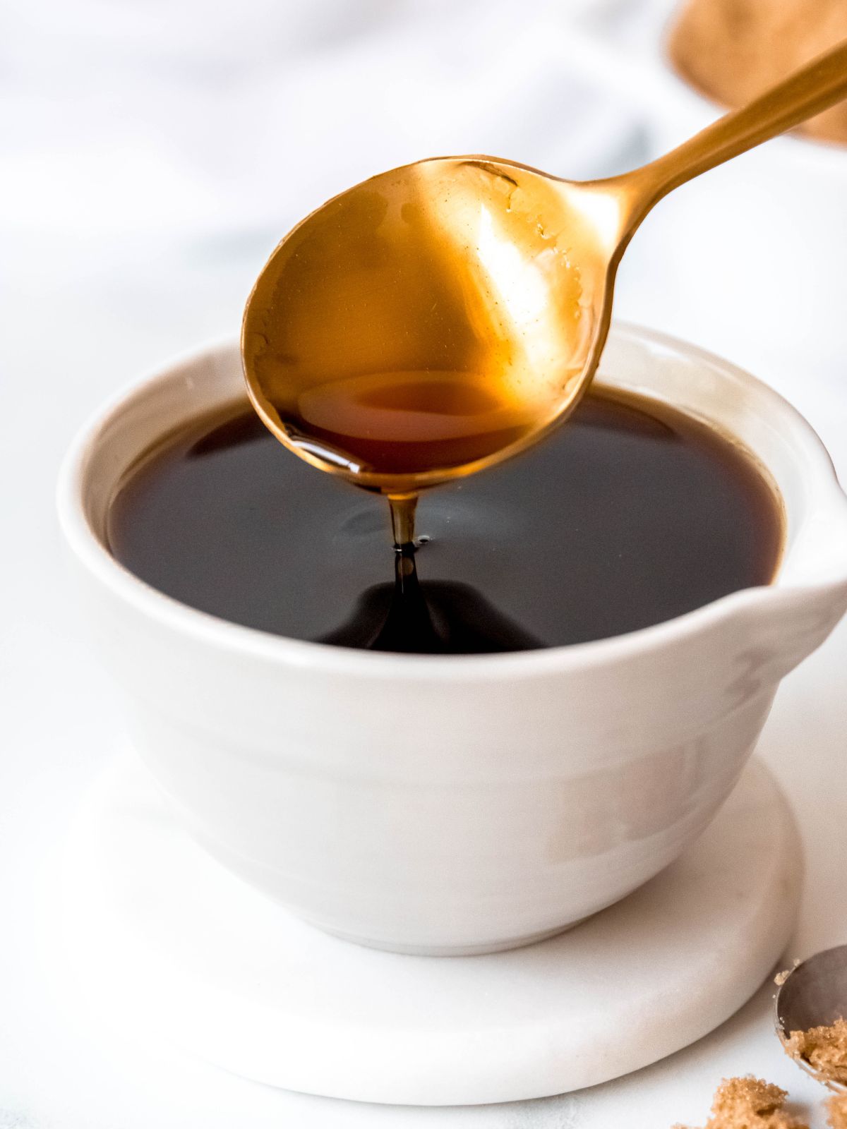 side on shot of a spoon dipping into a bowl of homemade brown sugar simple syrup.