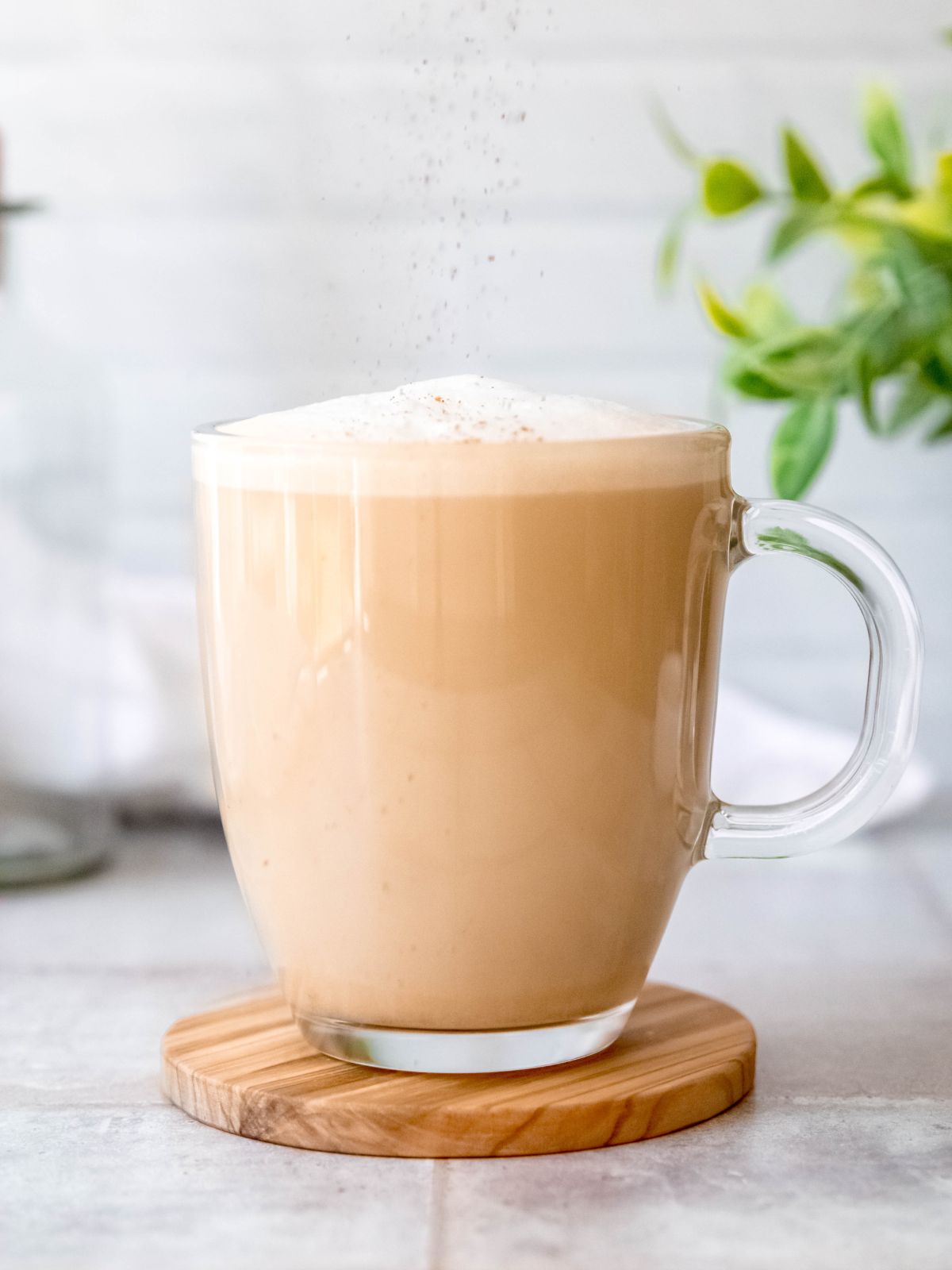 action shot of cinnamon being sprinkled on the oat milk latte.