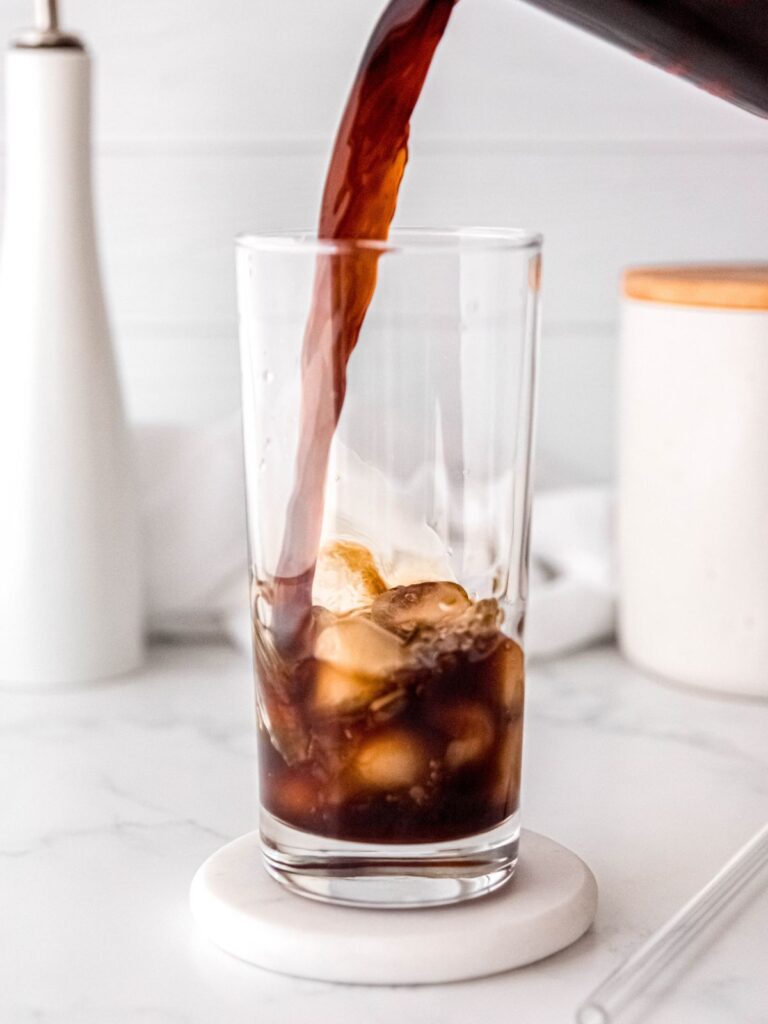 action shot of cold brew coffee being poured over the ice.