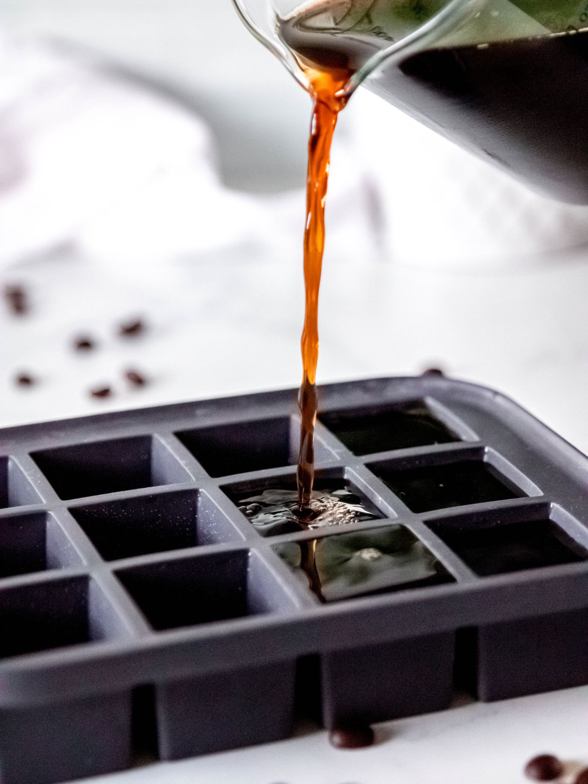 action shot of pouring chilled coffee into ice cube trays.