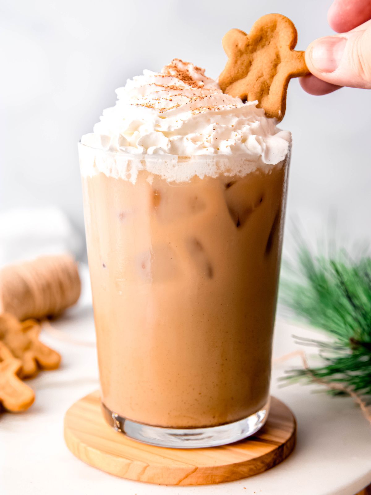Topping a glass of iced gingerbread chai latte with a gingerbread man.