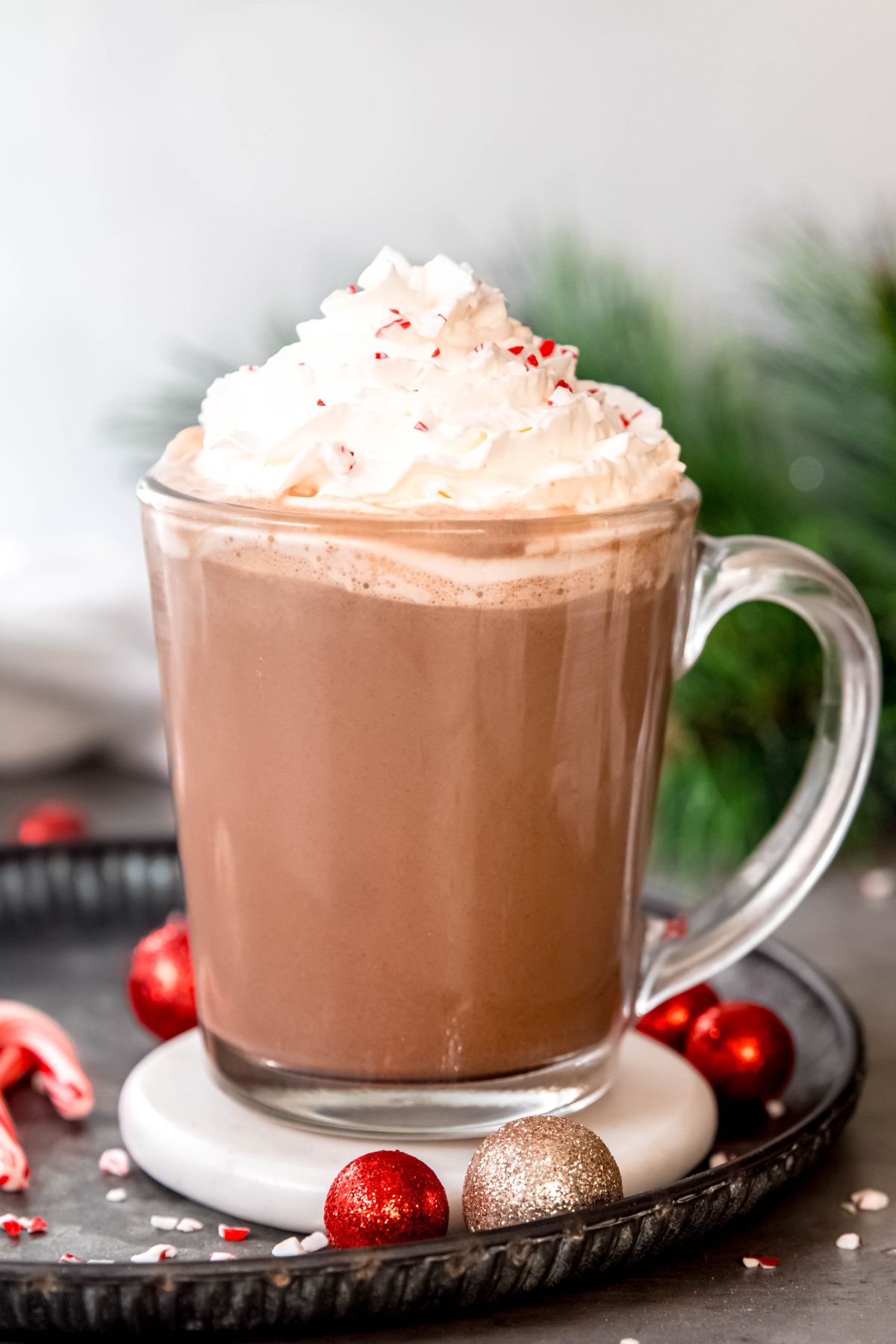 side on shot of a clear glass mug filled with peppermint mocha and topped with whipped cream and crushed candy canes like starbucks.