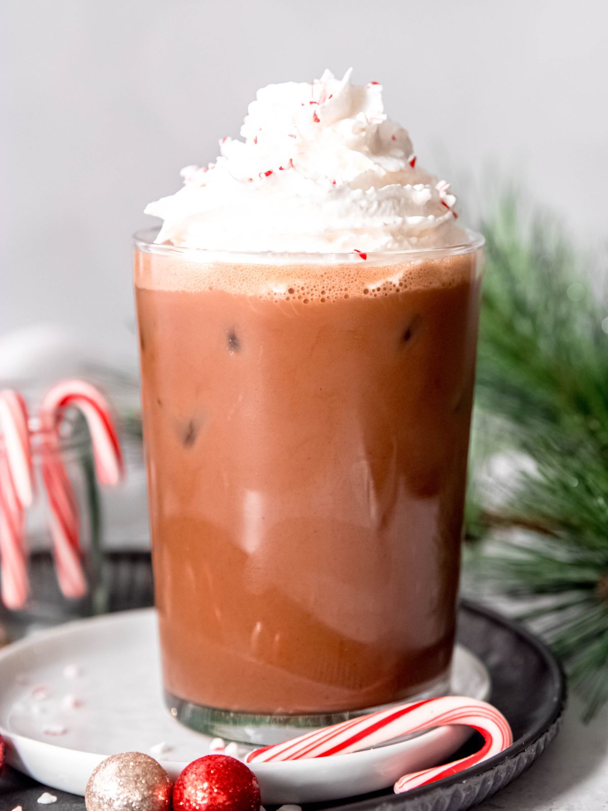 side on hero shot of an iced peppermint mocha topped with whipped cream and crushed peppermint candies a la Starbucks.