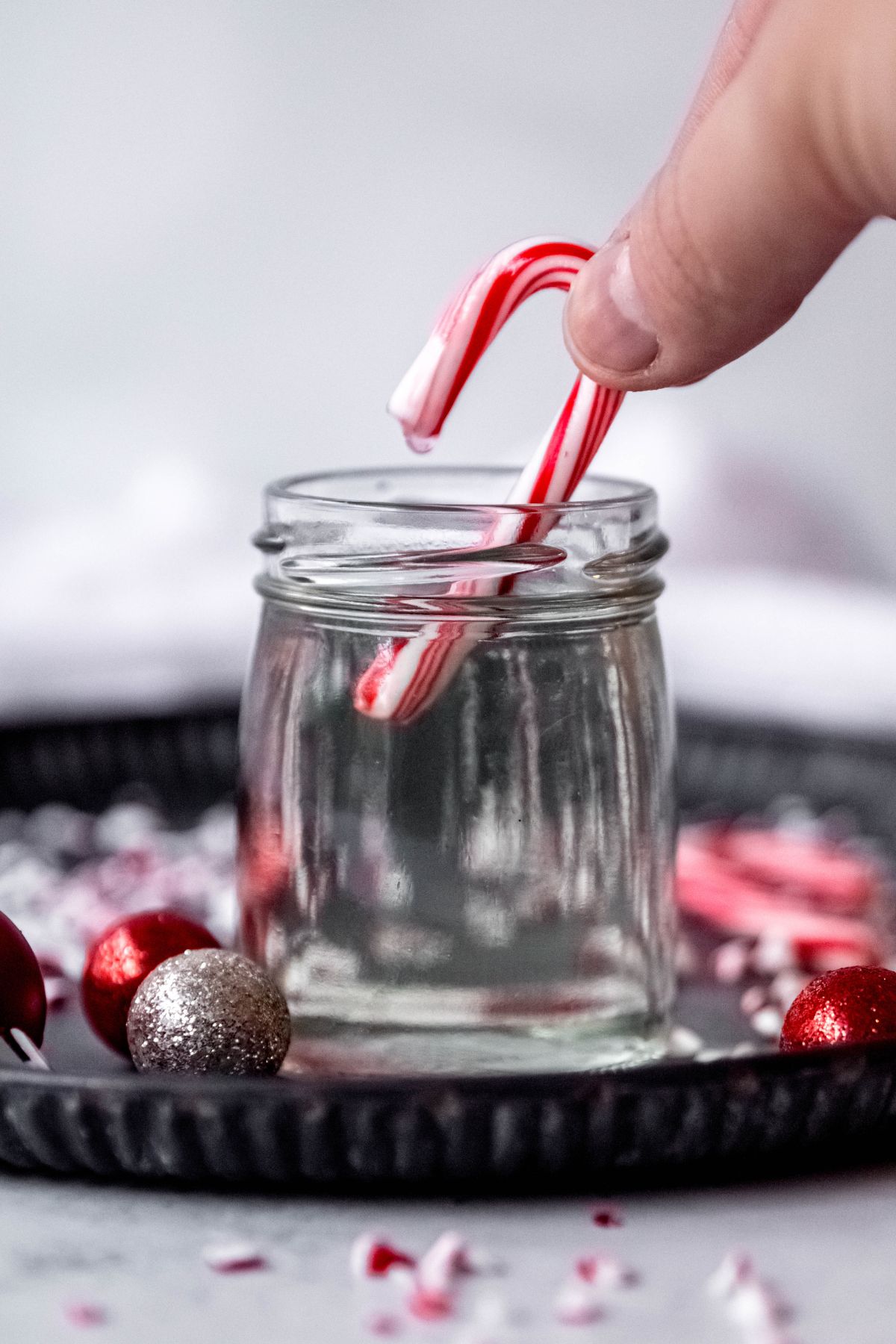 hand dipping a candy cane into the peppermint syrup.