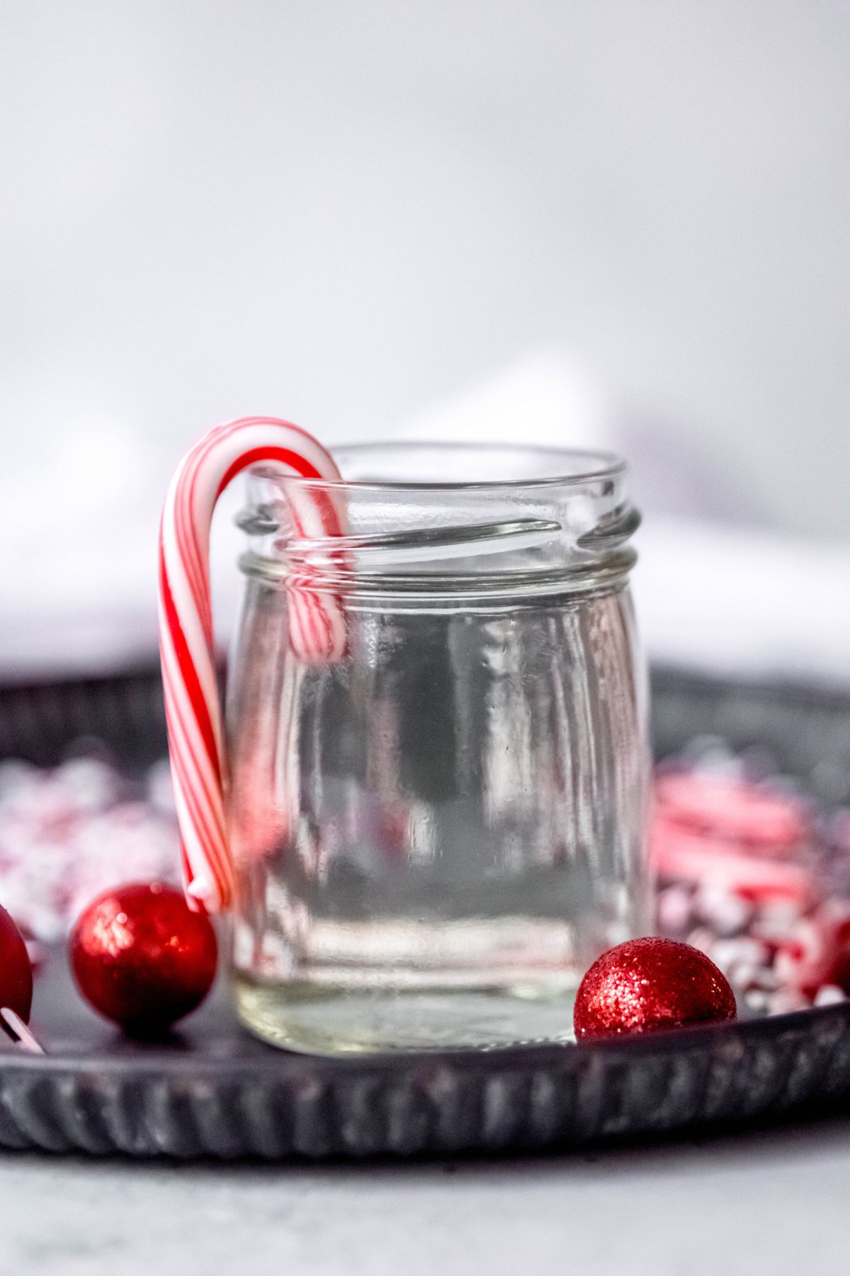 peppermint coffee syrup in a clear glass jar surrounded by candy canes.