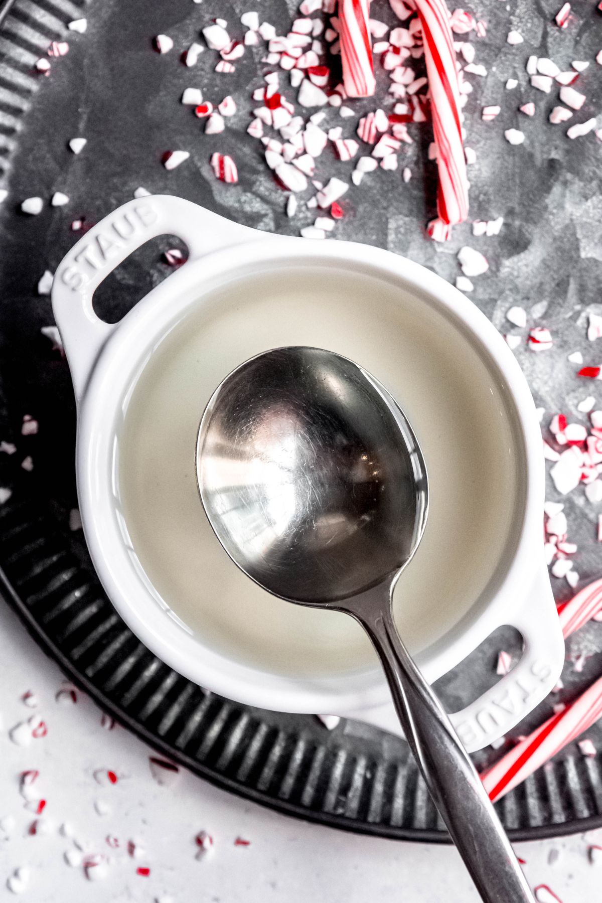 flat lay shot of a white bowl filled with peppermint simple syrup with a silver spoon removing some to put in coffee.