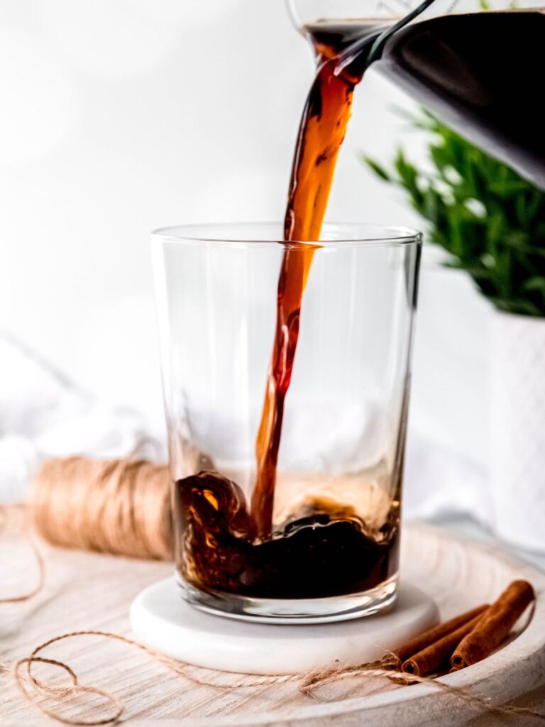 Pouring cold brew into a large glass cup. 