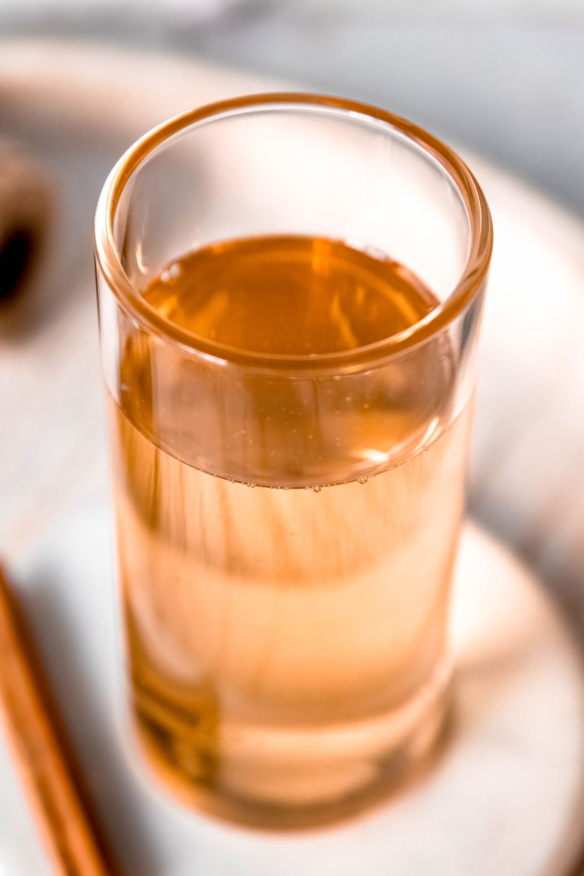 45 degree angle shot of a collins glass filled with light amber-colored cinnamon syrup.