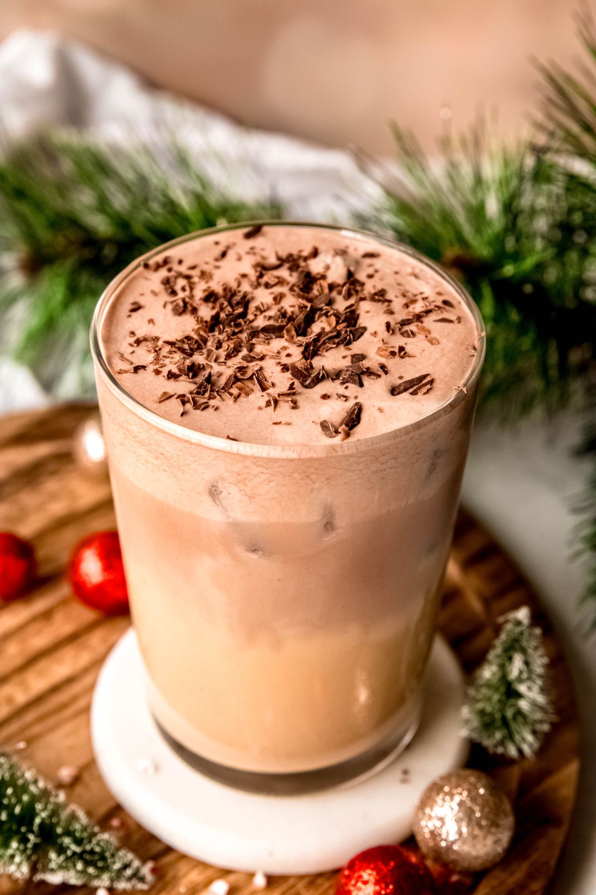 iced white mocha topped with chocolate peppermint cream cold foam and chocolate shavings on a wooden tray.