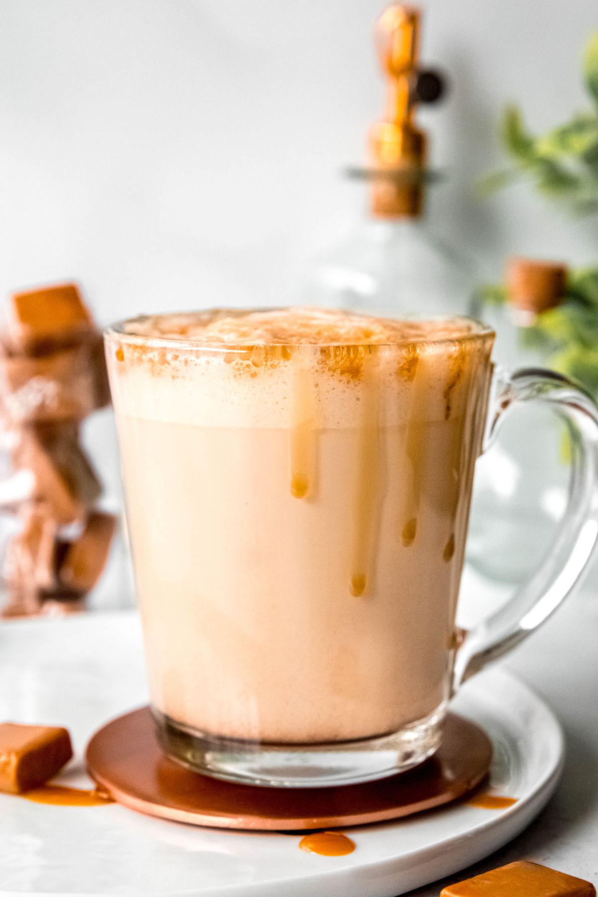 side on shot of a caramel-drizzled caramel latte in a clear glass mug.