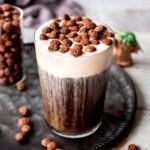 square hero image of a homemade Disney Black Caf Cold Brew topped with cocoa puffs.