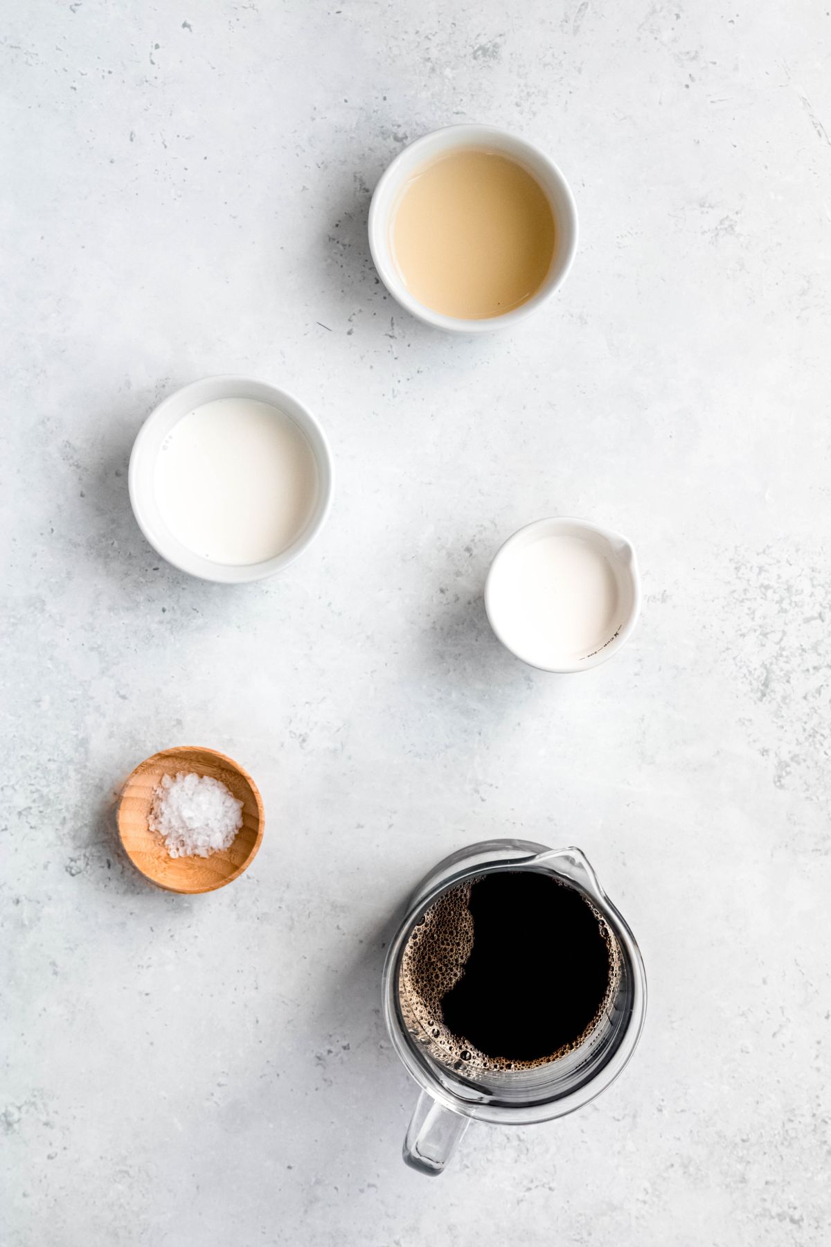 ingredients needed to make salted caramel cream cold brew measured out into bowls on a white table.