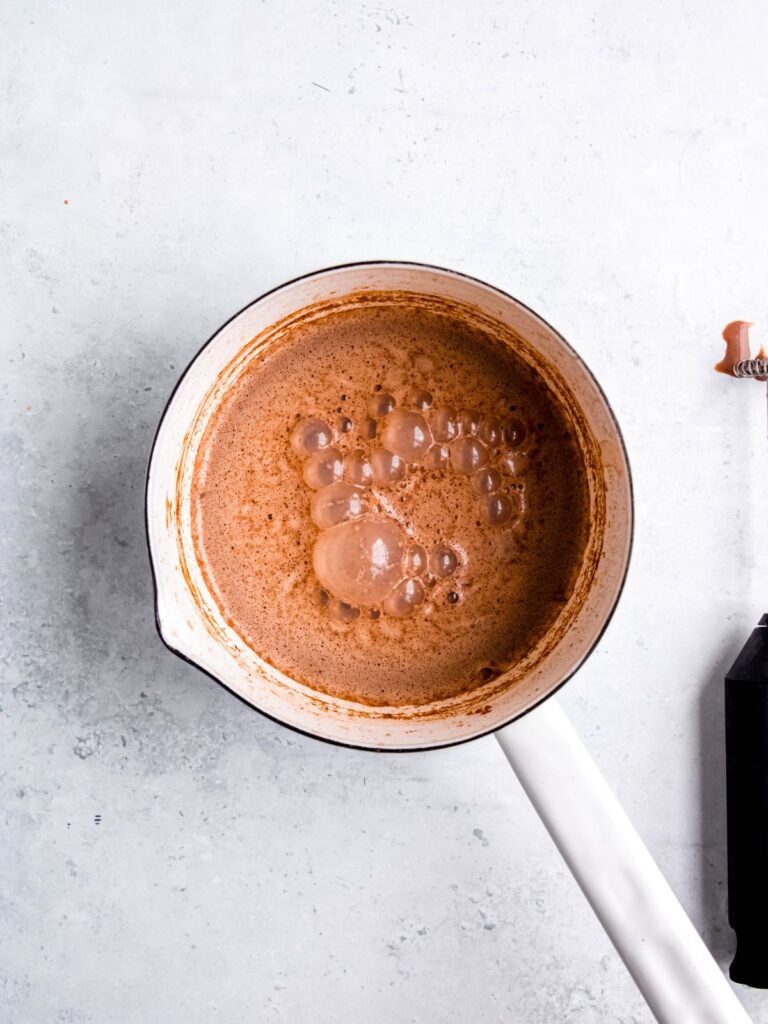 A small white sauce pan of frothed chocolate milk mixture.