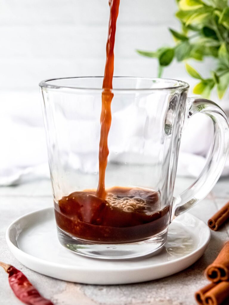 Pouring espresso into a glass coffee mug.