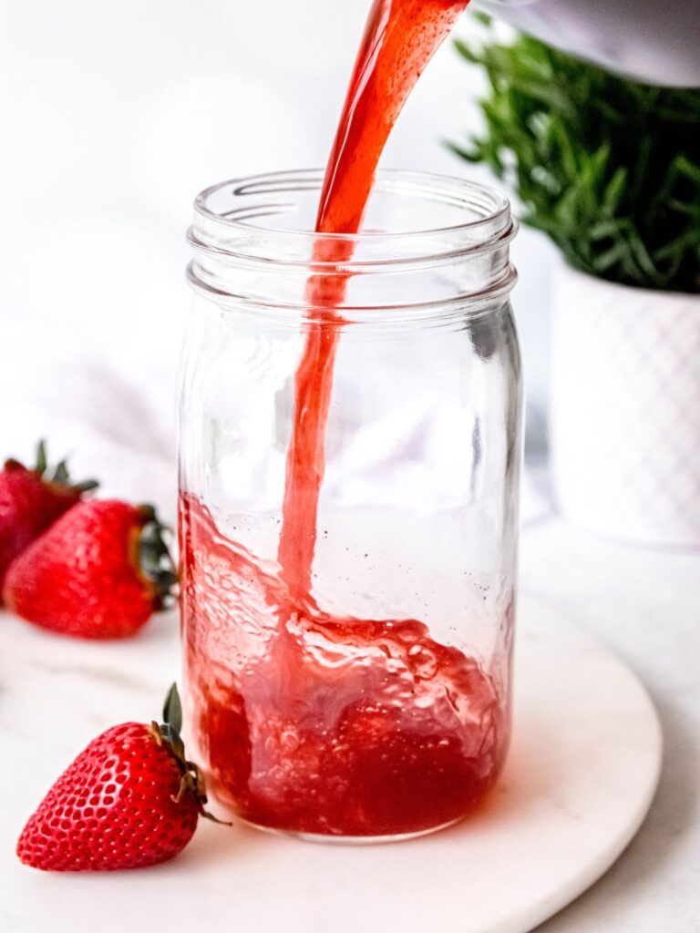 pouring the strawberry acai refresher base into a jar to cool. 