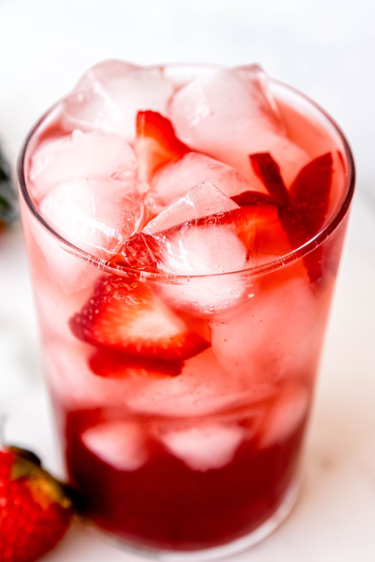 closeup 45 degree angle of a homemade strawberry acai refresher over ice. 