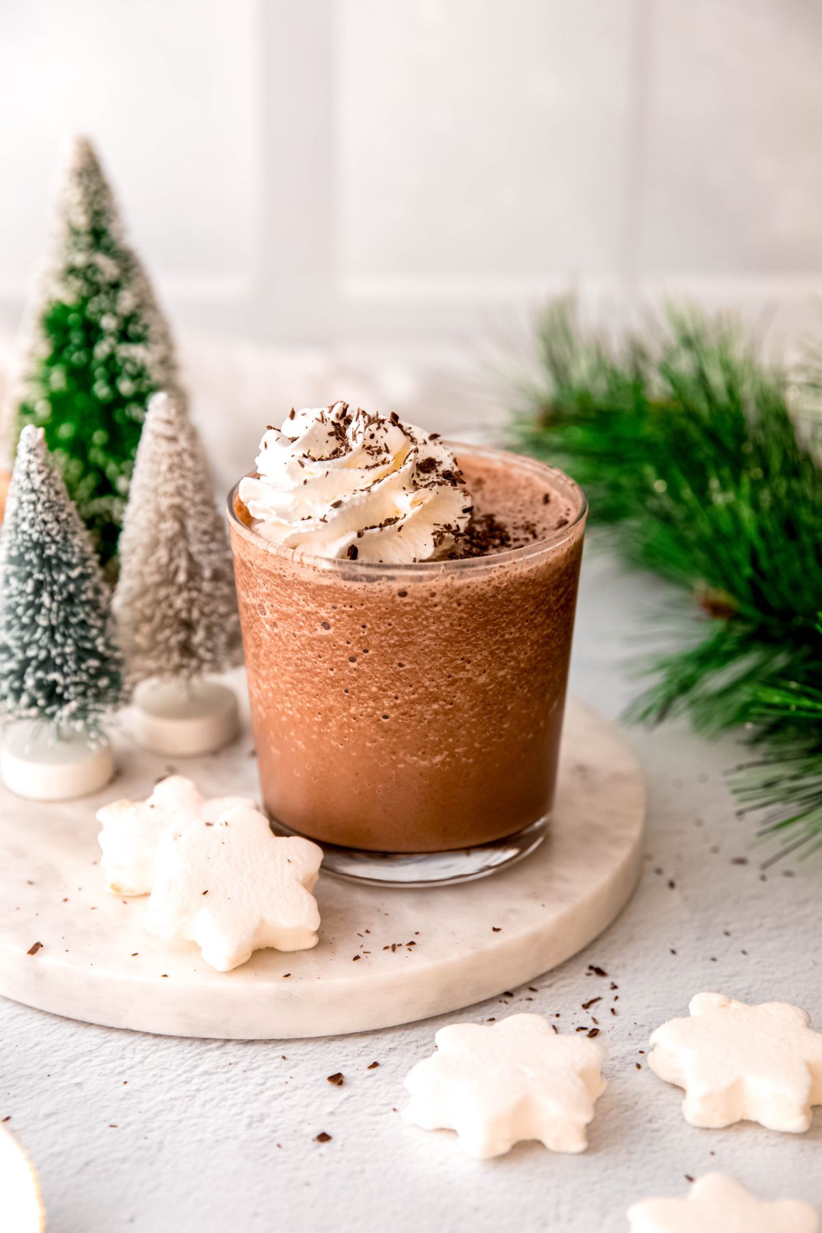 A close-up angled shot of a small glass of frozen hot chocolate topped with whipepd cream and shaved chocolate. 
