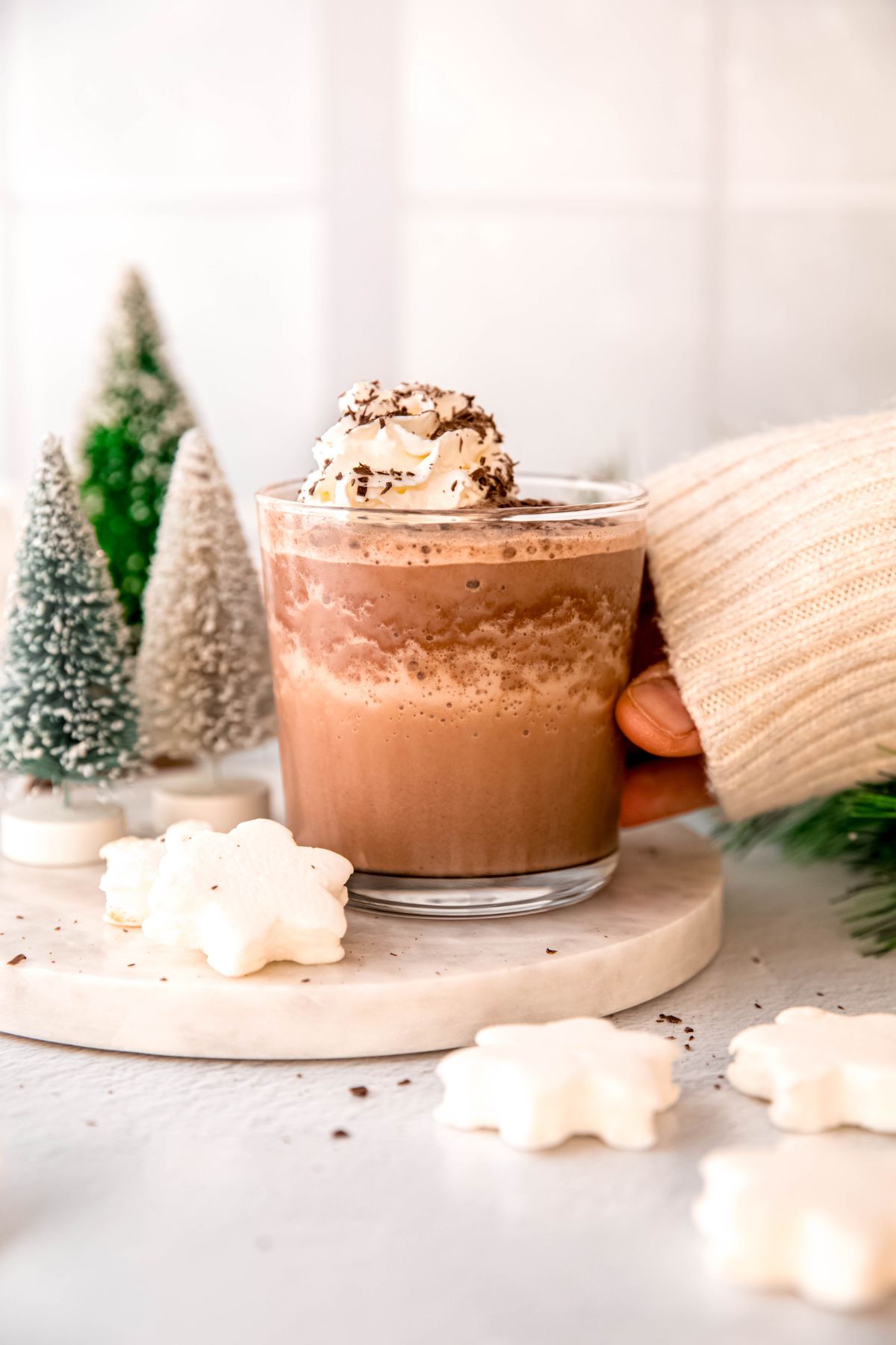 A hand reaching in for a glass of frozen hot chocolate on a marble surface.