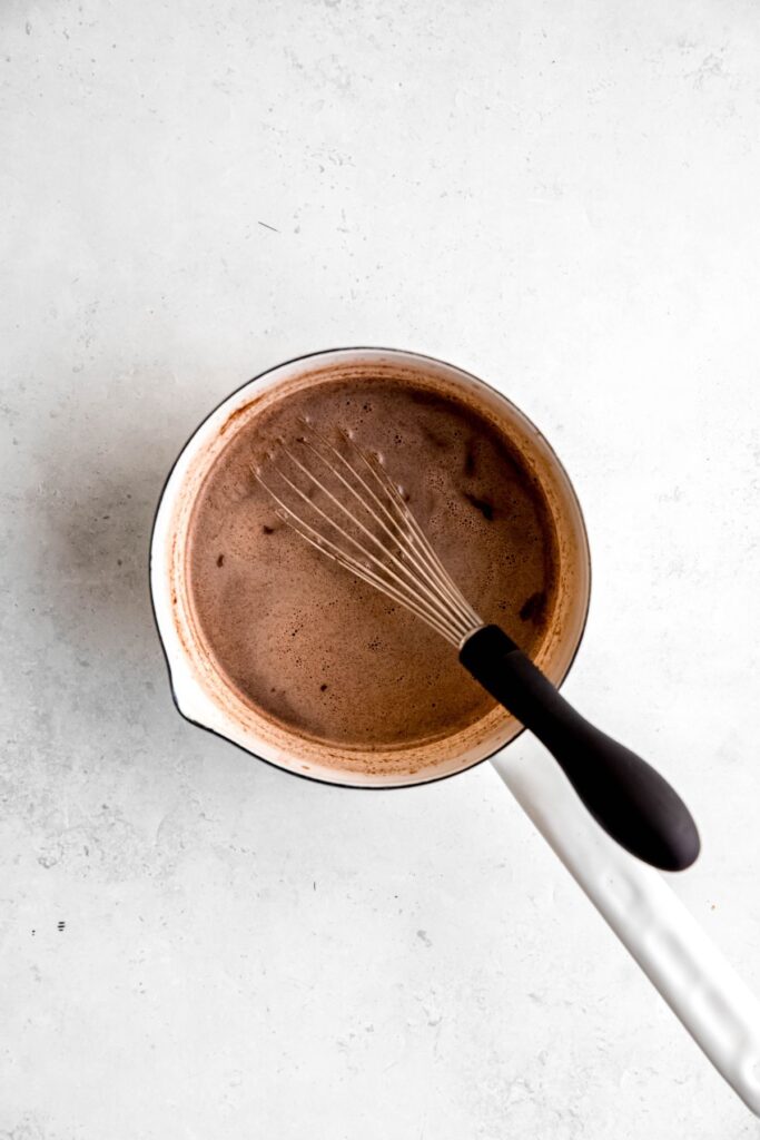 A saucepan of the gingerbread hot cocoa recipe with a whisk. 