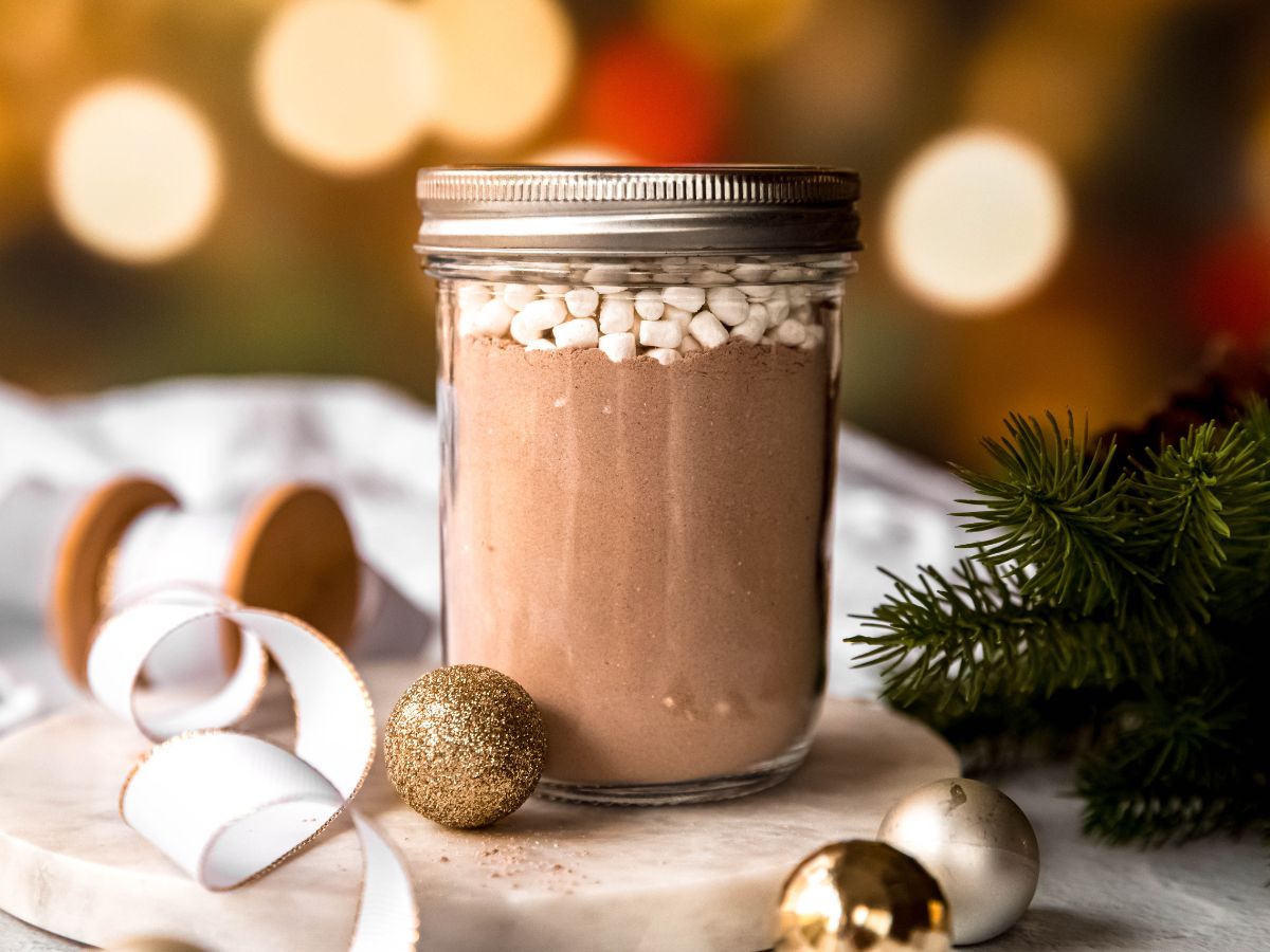 A side horizontal shot of a mason jar of homemade cocoa mix topped with dehydrated marshmallows. 