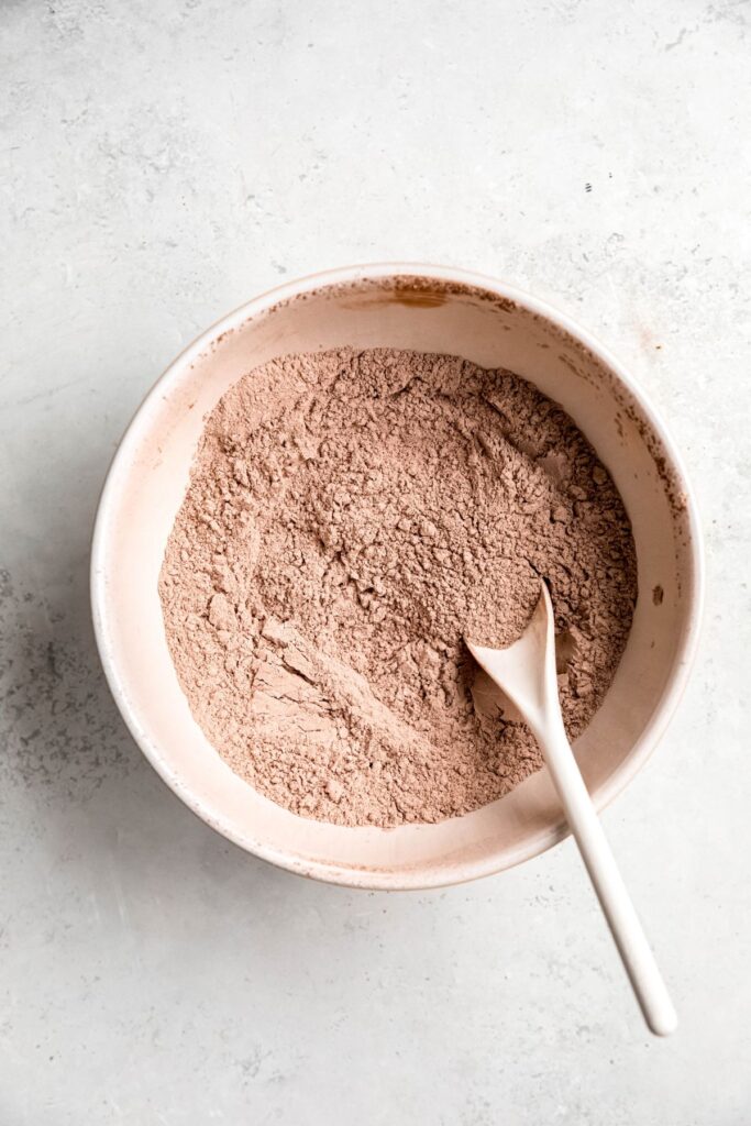 Homemade hot chocolate mix in a mixing bowl with a stir spoon.