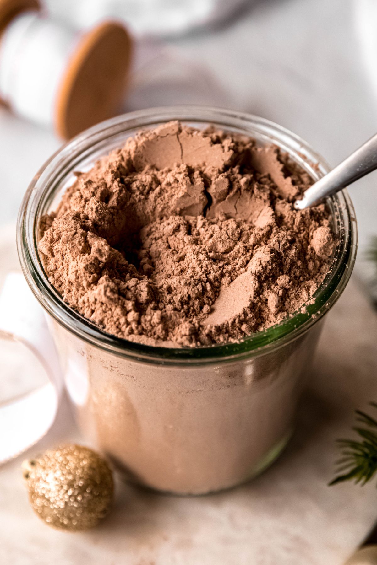 A close-up angled shot of a cup of cocoa mix with a spoon in it. 