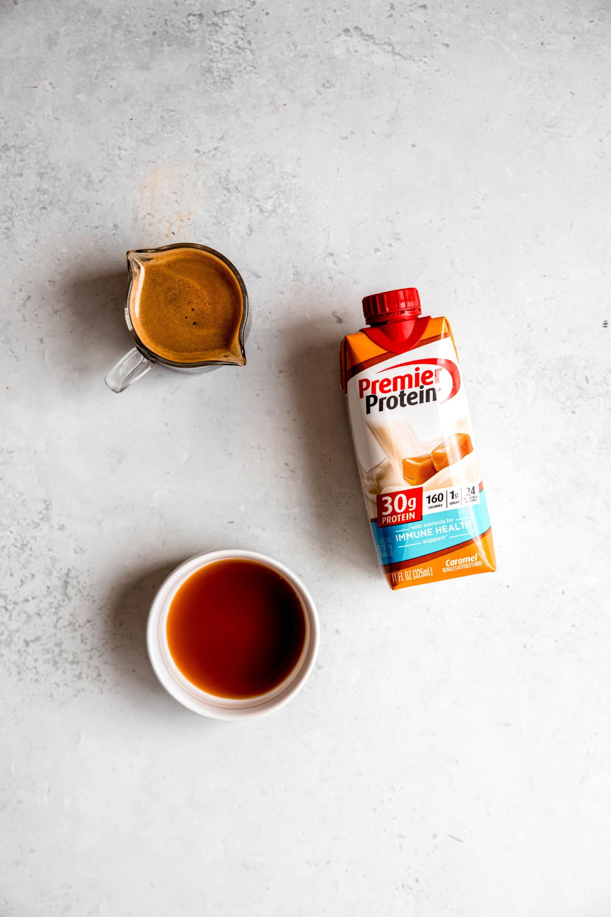 All the ingredients needed to make protein iced coffee: espresso, a premade protein shake, and caramel syrup. 