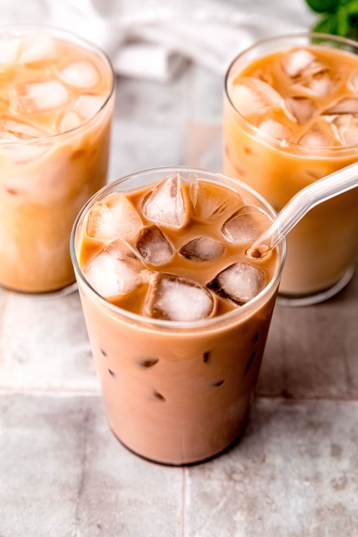 A close-up overhead shot of three tall glasses of protein iced coffee on the counter. 