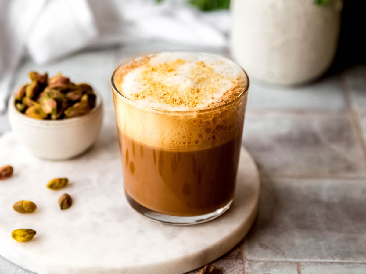 horizontally framed hero shot of a DIY pistachio cortado (starbucks copycat) make with oat milk. 