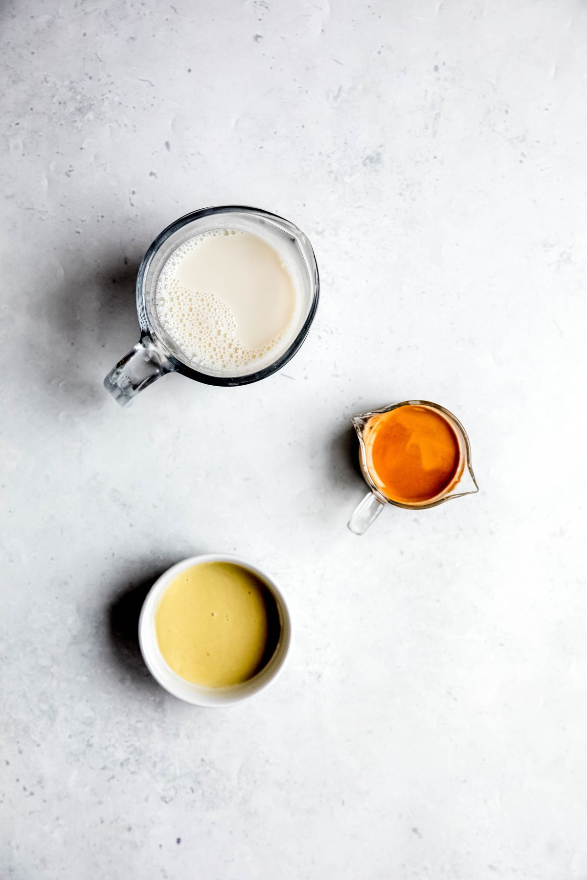 ingredients needed to make a starbucks pistachio oatmilk cortado at home measured out on a white table. 