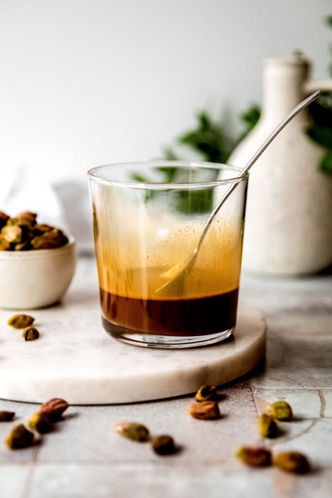 the espresso in the glass after mixing with the pistachio sauce with a silver spoon; the color is slightly lighter than before. 