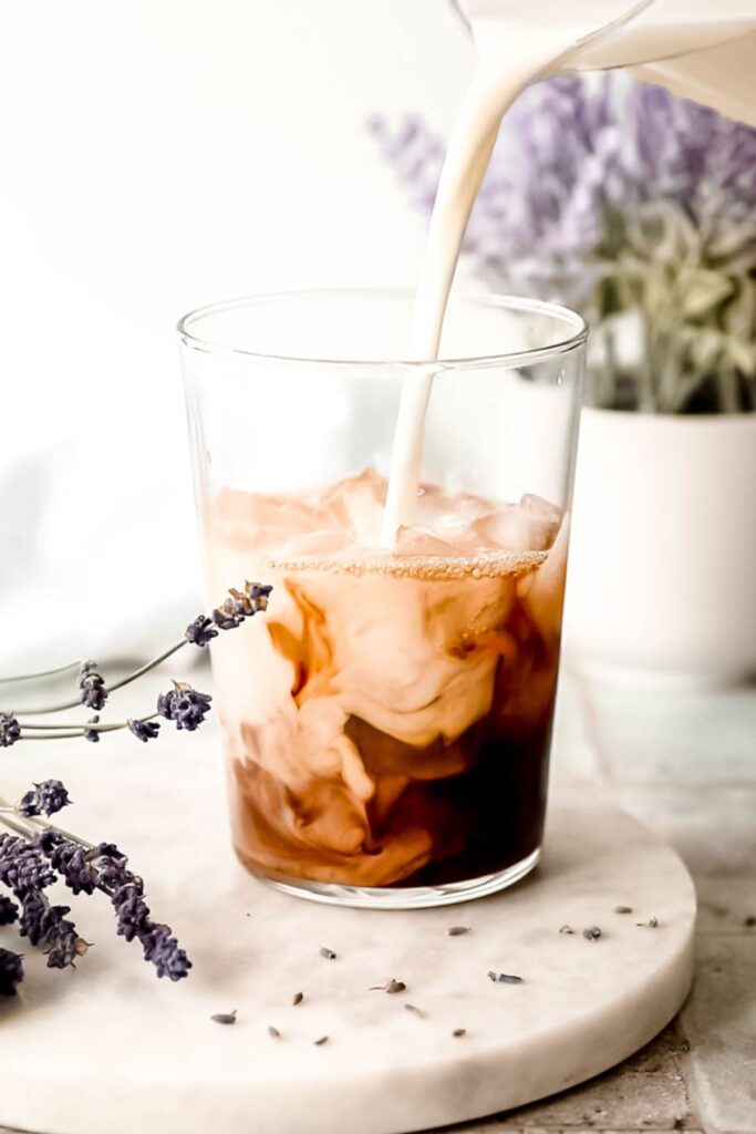 Pouring milk into a glass of chai concentrate. 