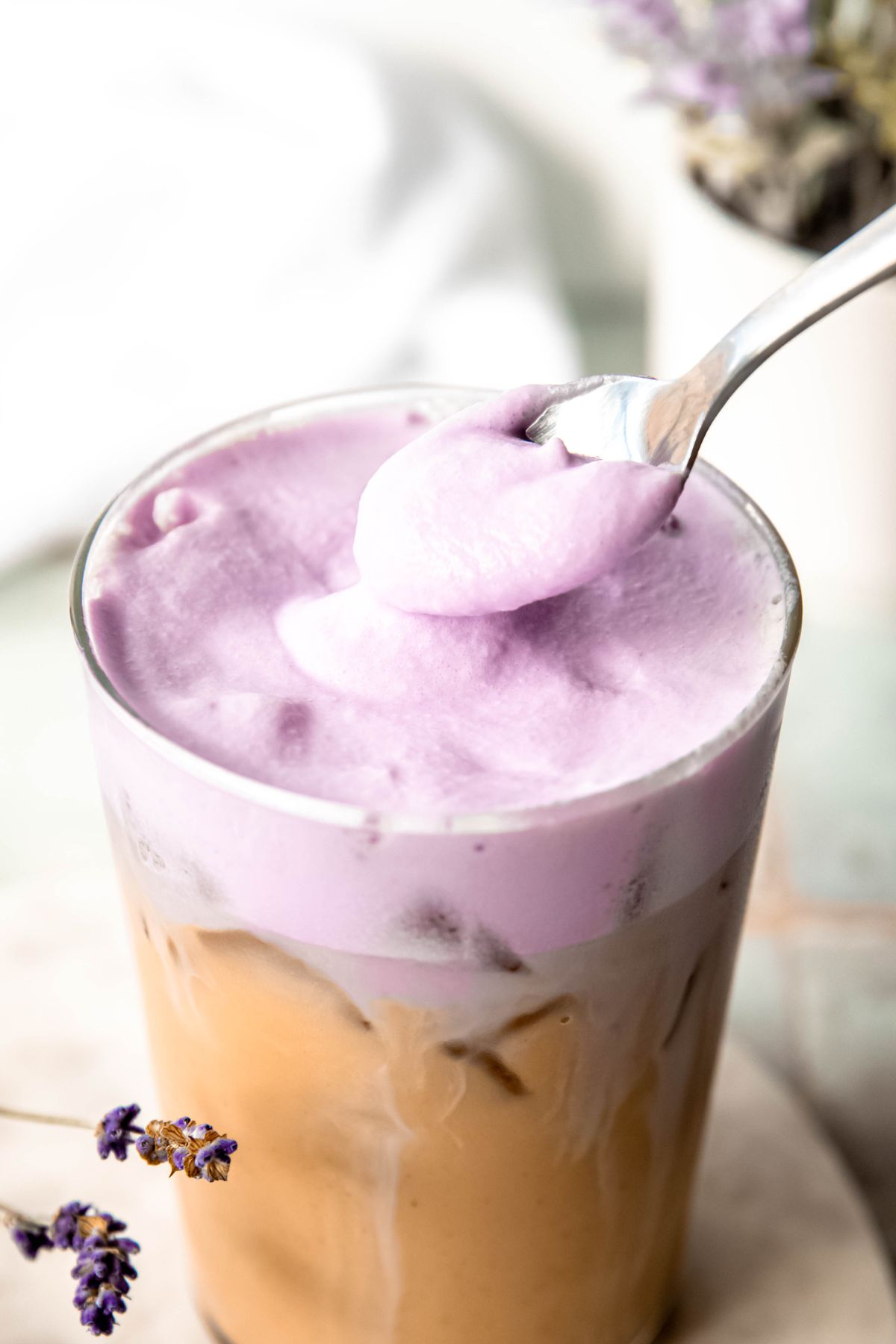 silver spoon dolloping lavender cold foam on an iced latte. 