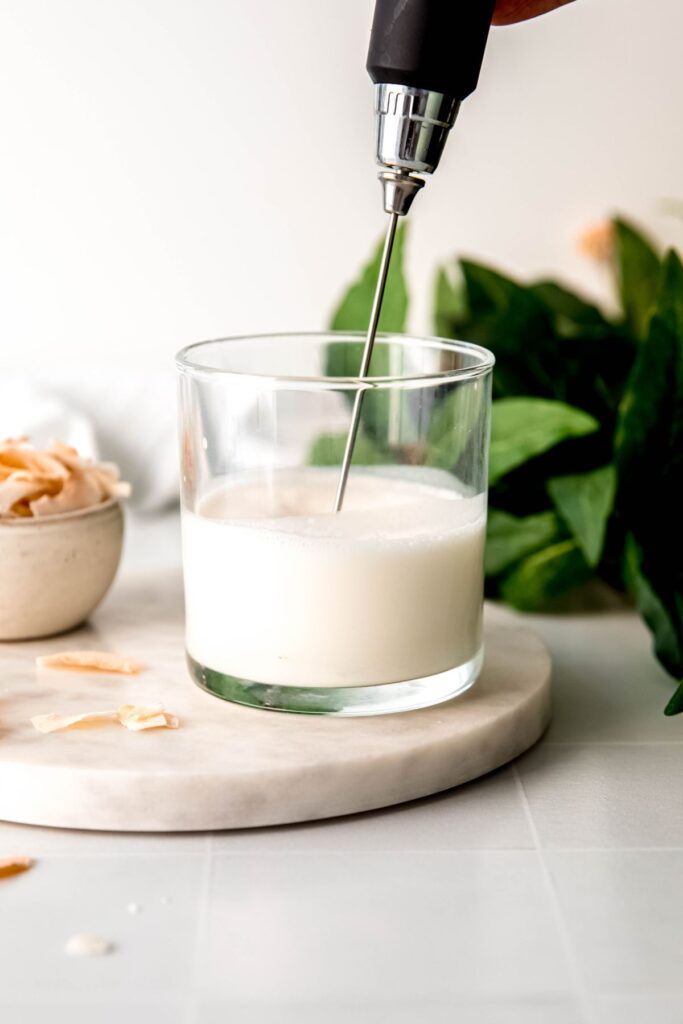 Whipping up the coconut cream cold foam in a small glass. 