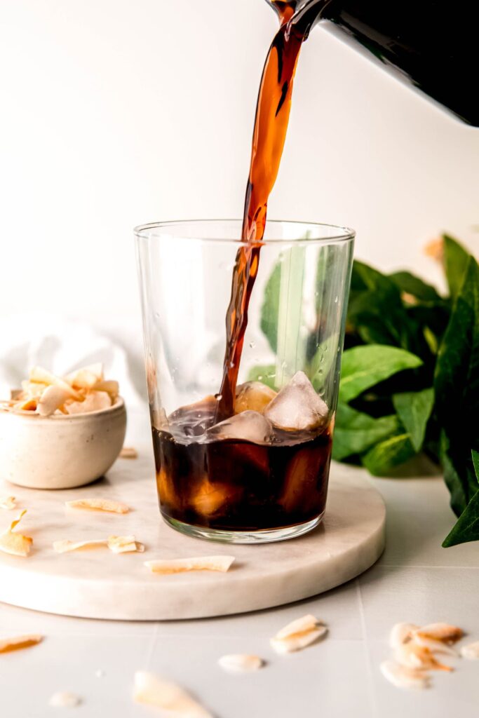 Pouring the coconut cold brew into a tall glass with ice. 