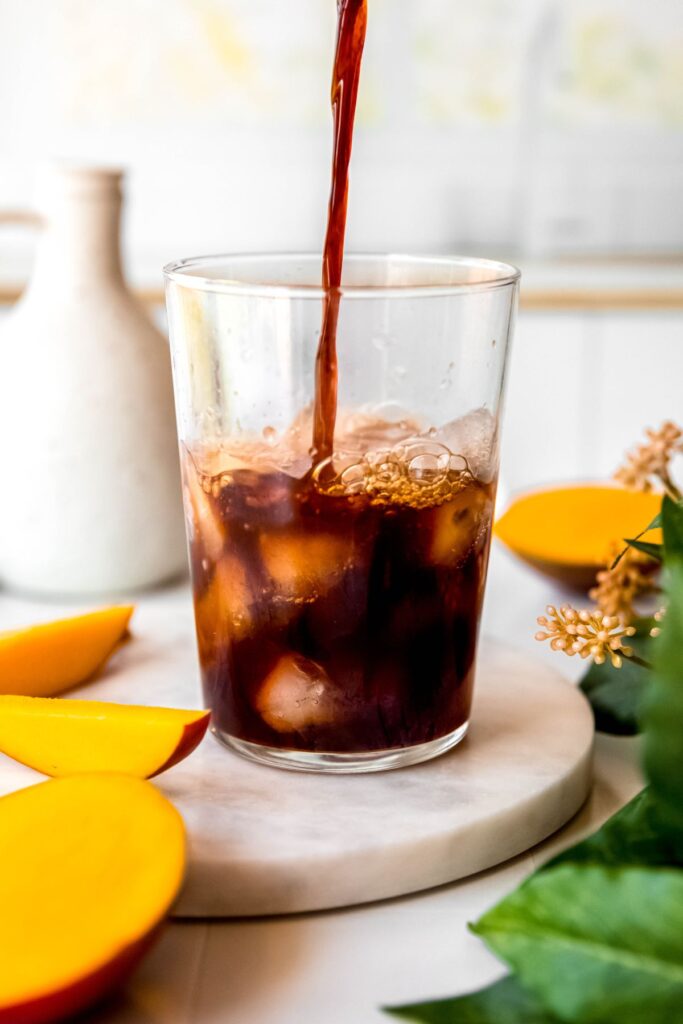 action shot of chai concentrate being poured into a glass of ice. 
