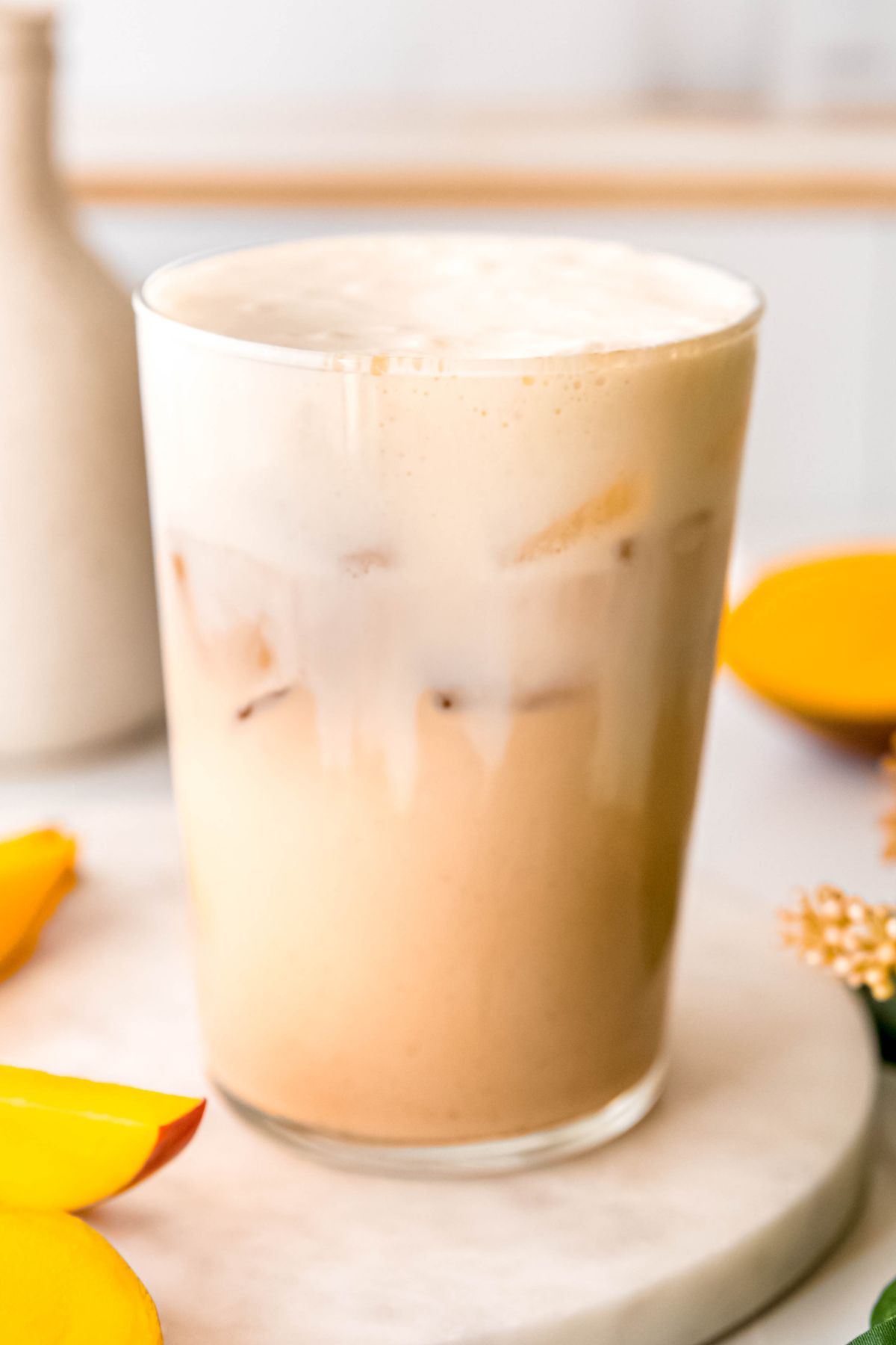 closeup shot of a DIY Starbucks iced mango cream chai latte in a clear pint glass. 