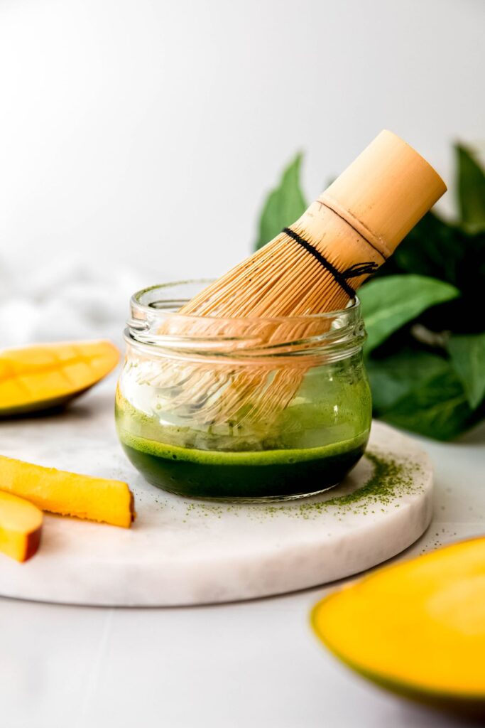 bamboo matcha whisk in a small jar with matcha after whisking with hot water until frothy. 