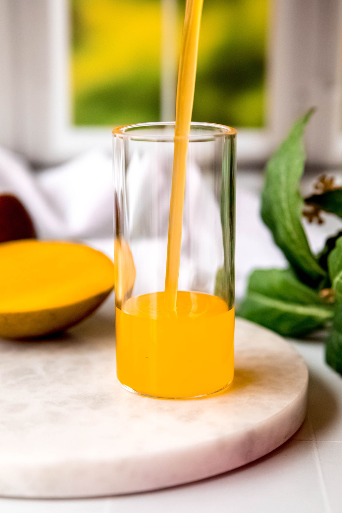 action shot of all-natural mango syrup being poured into a collins glass. 