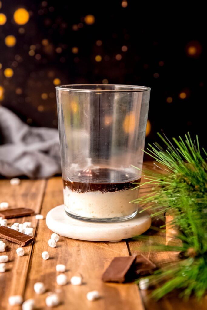 whipped cream in the bottom of a pint glass topped with a layer of mocha sauce.