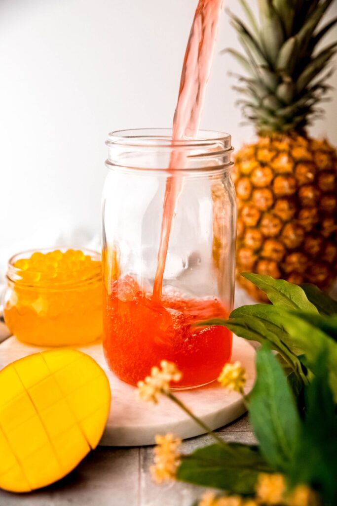 action shot of a the tropical butterfly refresher base being poured into a mason jar to cool. 