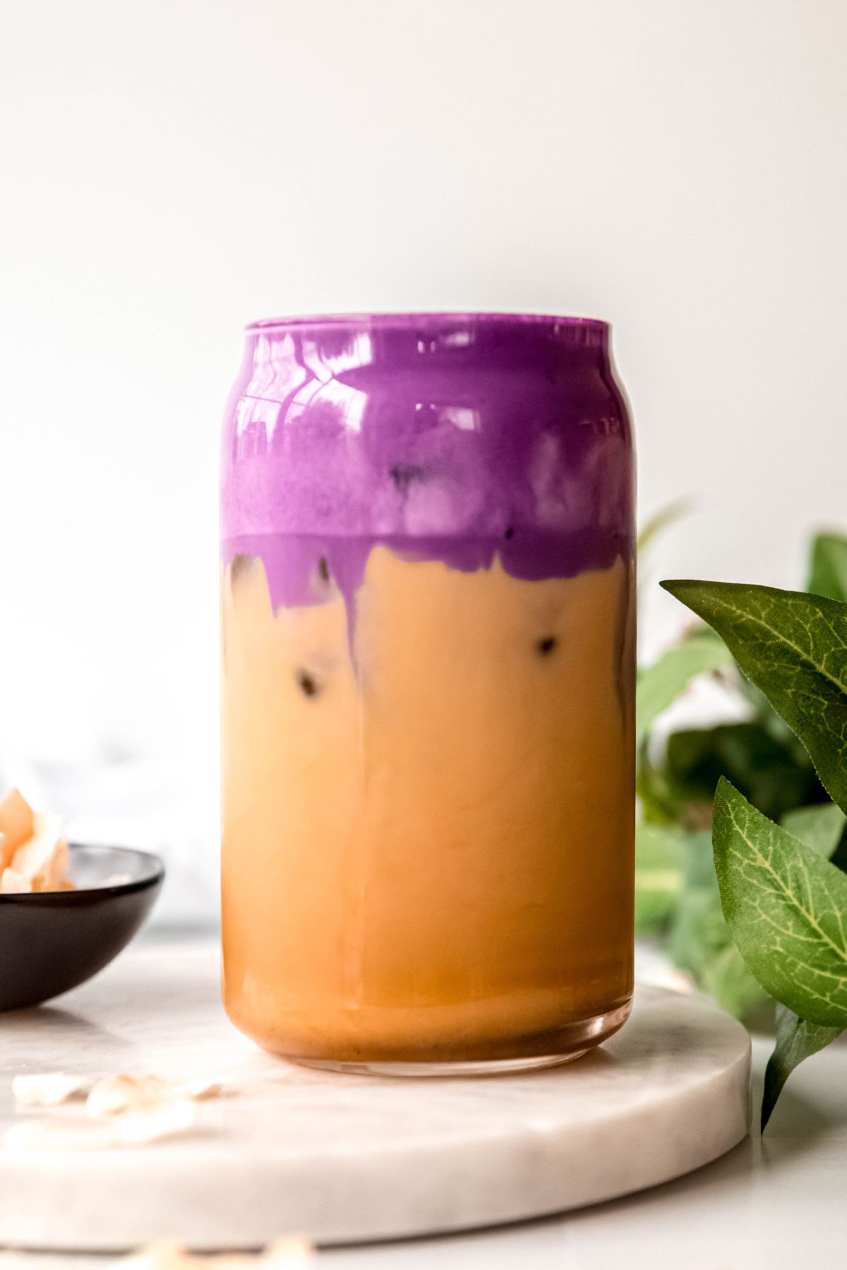 side on view showing a homemade iced coconut shaken espresso topped with vibrant purple ube coconut cream cold foam. 